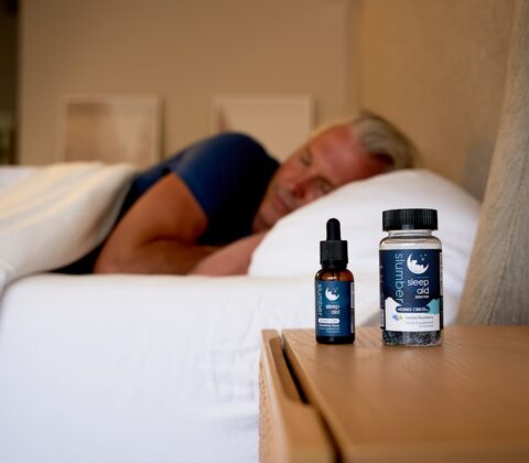 a man sleeping on a bed next to a bottle of cb