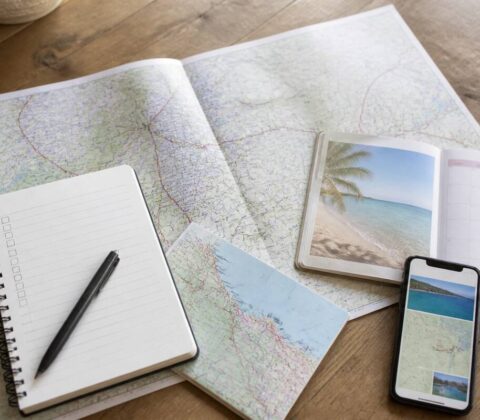 Checklist om vakanties te vergelijken: een notitieboek, reiskaart en smartphone op tafel