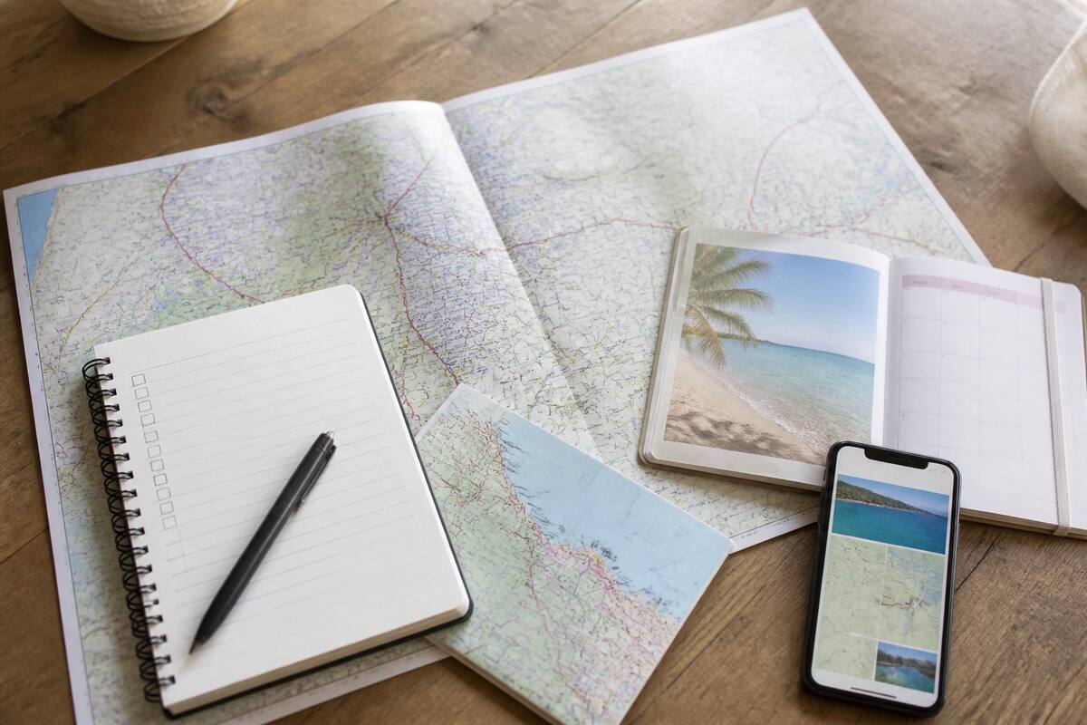 Checklist om vakanties te vergelijken: een notitieboek, reiskaart en smartphone op tafel